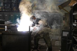 Trabalhador com máscara de proteção em ambiente industrial tomado por fumaça