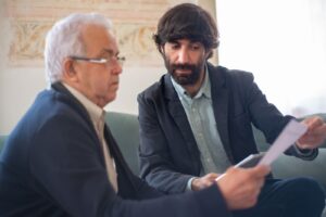 Advogado mostra documento a cliente idoso durante conversa sobre desconto no benefício do INSS