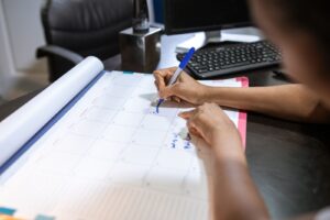 Pessoa anotando datas em um calendário de mesa no escritório