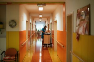 Profissional de enfermagem empurrando um carrinho no corredor de um hospital durante o plantão.