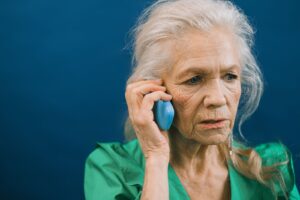 Mulher idosa ao telefone com expressão apreensiva
