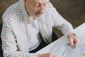 Homem idoso de oculos analisando documentos em casa