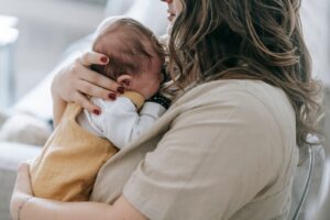 Mãe segura o bebê recém-nascido no colo, em casa