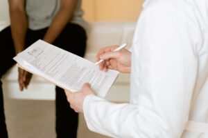 Médico revisa relatório e prescrição em prancheta durante consulta em consultório.