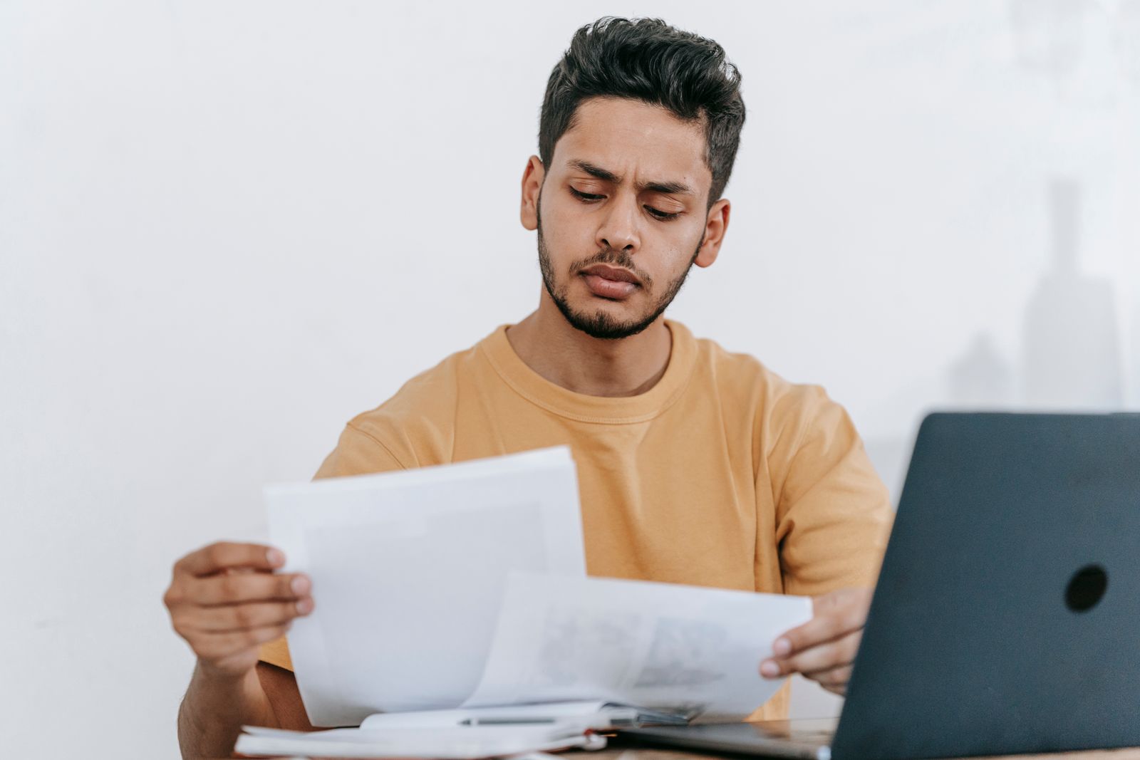 Homem confere documentos de rescisão com expressão de dúvida