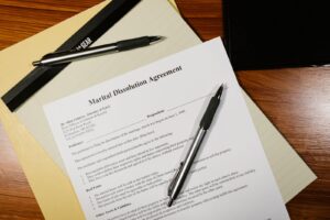 Formulario de acordo de dissolucao conjugal sobre uma mesa, com canetas e pastas de documentos.
