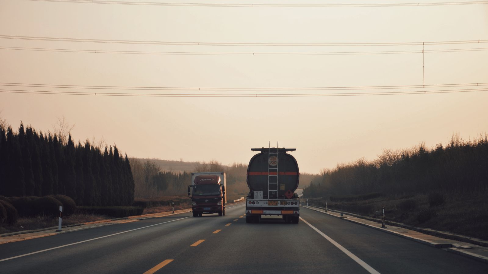 Caminhões trafegando em rodovia ao entardecer